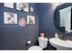 Chic powder room with navy walls, decorative artwork, and unique mirror at 431 Courtfield Way, Castle Pines, CO 80108