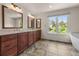 Bathroom features dual sinks, wood cabinetry, tile floor and a large window with backyard views at 1564 S Uinta Way, Denver, CO 80231