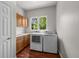 Bright laundry room with wood cabinets, white countertops, washer and dryer, and large window at 1564 S Uinta Way, Denver, CO 80231