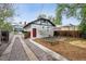 White brick house with a red door, wooden fence, gravel driveway, and a patio at 1736 Grove St, Denver, CO 80204