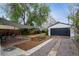Landscaped backyard with patio, gravel driveway, garden plot, and detached garage at 1736 Grove St, Denver, CO 80204