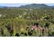 Aerial view of a luxurious home nestled among lush green trees and mountains in the distance at 2873 Cortina Ln, Evergreen, CO 80439