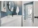 Modern bathroom featuring a round mirror, decorative black fixtures, and patterned floor tiles connecting to an adjacent bedroom at 2873 Cortina Ln, Evergreen, CO 80439