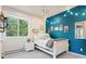 Colorful bedroom with a white daybed, bright turquoise accent wall, and modern lighting fixtures at 2873 Cortina Ln, Evergreen, CO 80439