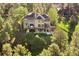 View of home with large windows, deck, and fenced yard among mature trees at 2873 Cortina Ln, Evergreen, CO 80439