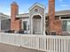 Front view of townhouse with gray siding, brick accents, and white picket fence at 9051 Bear Mountain Dr, Highlands Ranch, CO 80126