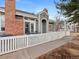 Townhouse entrance with patio, white fence, and brick accents at 9051 Bear Mountain Dr, Highlands Ranch, CO 80126