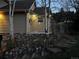 Charming home exterior featuring a unique stone foundation, mature trees, and decorative string lights at 26212 Center Dr, Kittredge, CO 80457