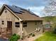 Exterior view of home showcasing solar panels, stone accents, and easy access to the backyard at 26212 Center Dr, Kittredge, CO 80457