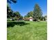 Large backyard features a lush lawn, mature trees, and a charming home in the background at 9640 W Chatfield Ave # A, Littleton, CO 80128