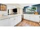 Bright kitchen featuring white cabinets, wood floors, stainless steel appliances, and a large window overlooking the backyard at 1260 Hoyt St, Lakewood, CO 80215