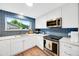 Modern kitchen with white cabinets, blue backsplash, stainless steel appliances and hardwood floors at 1260 Hoyt St, Lakewood, CO 80215