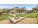 Landscaped backyard features a stone patio with a fire pit, green lawn, and deck at 19210 E Pacific Pl, Aurora, CO 80013