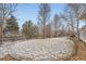 Spacious backyard with trees, a wooden fence and snow covered grass at 8385 Briar Trace Dr, Castle Pines, CO 80108