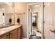 Bright bathroom featuring a vanity with storage, a mirror and a doorway to a bedroom at 8385 Briar Trace Dr, Castle Pines, CO 80108