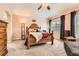 Bedroom with carpet, light pink walls, ceiling fan, large window, and a wooden sleigh bed at 8385 Briar Trace Dr, Castle Pines, CO 80108