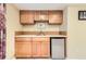 Basement wet bar featuring wood cabinetry, countertop, sink, mini-fridge, and neutral paint at 8385 Briar Trace Dr, Castle Pines, CO 80108