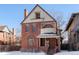 Brick two-story home with a wrap-around porch and snow-covered lawn at 1340 N Gilpin St, Denver, CO 80218