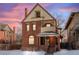 Brick two-story home with a wrap-around porch and snow-covered lawn at 1340 N Gilpin St, Denver, CO 80218