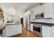 View of white kitchen featuring stainless steel appliances, stone countertops, and a view into the adjacent living space at 2765 W Denver Pl, Denver, CO 80211