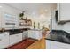 Bright kitchen with white cabinets, black countertops, stainless steel appliances, and decorative wooden shelves at 2765 W Denver Pl, Denver, CO 80211