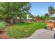 A fenced backyard featuring a lush lawn, mature tree, patio set, BBQ, and a shade sail, perfect for outdoor entertaining at 3775 S Green Ct, Englewood, CO 80110