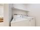 Bright laundry room featuring a white washer, dryer and shelf for convenient storage solutions at 4164 E 135Th Pl, Thornton, CO 80241