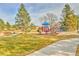 A vibrant playground with colorful equipment sits amidst a grassy park area with walking paths and mature trees at 4164 E 135Th Pl, Thornton, CO 80241