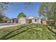 Inviting single-story home featuring a well-kept lawn, mature trees, and a convenient two-car garage at 1367 Teller St, Lakewood, CO 80214