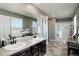 Bathroom with dual sinks, a large mirror, and a glass-enclosed shower at 975 Alta St, Lochbuie, CO 80603