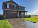 Two-story home with a well-manicured lawn, brown siding, stone accents, and a two-car garage at 975 Alta St, Lochbuie, CO 80603