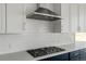 Up close image of a gas cooktop, range hood, and backsplash at 39441 Stockton Cir, Elizabeth, CO 80107