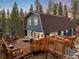 Charming barn style house with a wooden deck featuring outdoor seating, grill, and string lights in a wooded setting at 384 Blue Ridge Rd, Breckenridge, CO 80424