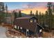 Exterior side view of a charming barn style home featuring a wooden deck and beautiful mountain views at sunset at 384 Blue Ridge Rd, Breckenridge, CO 80424
