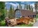 Charming barn style house with a wooden deck featuring outdoor seating, grill, and string lights in a wooded setting at 384 Blue Ridge Rd, Breckenridge, CO 80424
