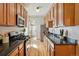 Well-appointed kitchen boasting wood cabinetry, black countertops, stainless steel appliances, and hardwood floors at 1239 N Lafayette St, Denver, CO 80218