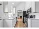 Bright kitchen featuring white cabinets, stainless steel appliances, and hardwood flooring at 6579 Ingalls St, Arvada, CO 80003