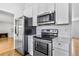 Well-equipped kitchen featuring stainless steel appliances, white cabinets, and hardwood flooring at 6579 Ingalls St, Arvada, CO 80003
