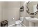 Powder room showcasing tile floors, pedestal sink, a decorative mirror, and toilet at 7310 Blue Water Dr, Castle Rock, CO 80108
