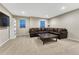 Bright living room with a dark leather couch, square coffee table, and white bookshelf with natural light at 7310 Blue Water Dr, Castle Rock, CO 80108