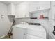 Functional laundry room with a washer, dryer, shelving and white cabinets for storage at 1857 W Tennessee Ave, Denver, CO 80223