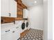 Laundry room with modern appliances, cabinetry, and patterned tile flooring at 5741 Doc Bar Circle, Larkspur, CO 80118