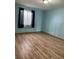 Bedroom with light wood floors, blue walls, and a window with black sheer curtains at 47904 Dartmouth Ave, Bennett, CO 80102