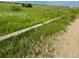 Scenic land with tall grass and a wooden beam, perfect for building your dream home at 47904 Dartmouth Ave, Bennett, CO 80102