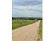 Gravel road leads to a rural property surrounded by open fields and distant trees, ideal for peaceful living at 47904 Dartmouth Ave, Bennett, CO 80102