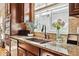 Detailed kitchen shot with granite countertops, stainless steel sink, dark wood cabinets, and mosaic tile backsplash at 6875 Northstar Ct, Castle Rock, CO 80108