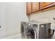 Modern laundry room featuring side-by-side washer and dryer beneath dark cabinets at 6875 Northstar Ct, Castle Rock, CO 80108