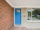 Close-up of a bright blue front door flanked by brick and stone and a view from the window of the outdoor scenery at 9120 W 3Rd Pl, Lakewood, CO 80226