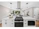 Modern kitchen with a central island featuring a cooktop and pendant lighting with a view of the living room at 9120 W 3Rd Pl, Lakewood, CO 80226