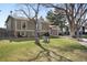 Charming two-story home featuring a well-maintained lawn, mature trees, and a cozy seating area at 9590 W Eureka Pl, Lakewood, CO 80227